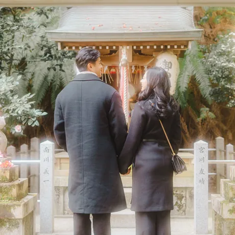 Priam and Eden walking toward a shrine gate under the blossoms